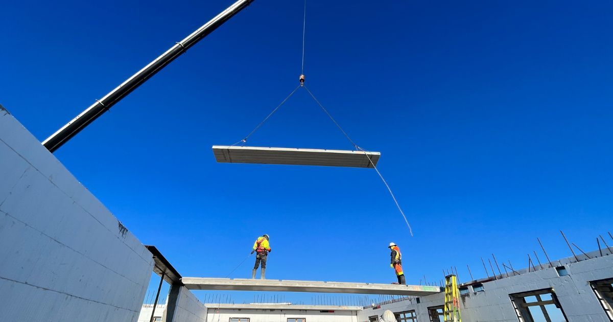 construction site with large crane moving concrete slab 